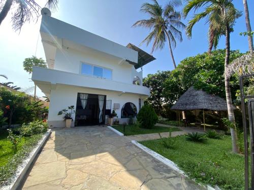 a white house with palm trees and a yard at Watamu House in Watamu