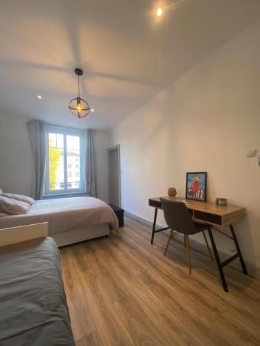 a bedroom with a bed and a desk and a window at Appartement hyper-centre Épinal in Épinal