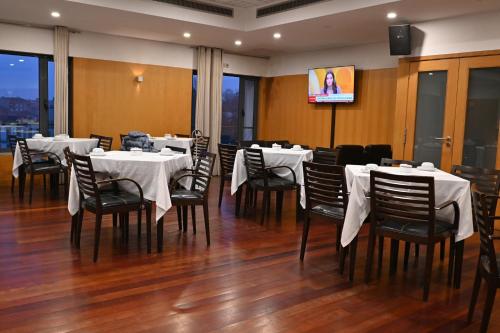a restaurant with white tables and chairs and a tv at Hotel Bagoeira in Barcelos