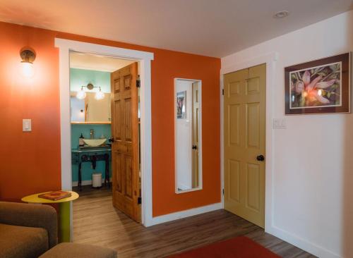 a living room with orange walls and a door at eARTh studios GallerySuite in Nelson