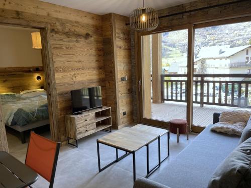 a living room with a couch and a table and a tv at Appartement Haut de Gamme neuf avec terrasse - 6 personnes - App 103 in Saint-Sorlin-dʼArves