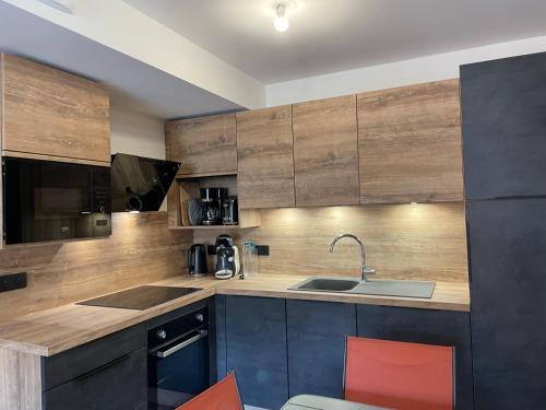 a kitchen with wooden cabinets and a sink at Appartement Haut de Gamme neuf avec terrasse - 6 personnes - App 103 in Saint-Sorlin-dʼArves