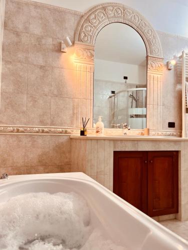 Un baño con bañera y un espejo grande. en House in Cave, en Massafra