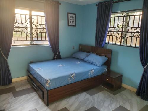 a bedroom with a bed with blue walls and windows at TwinVilleCove, affordable villas located in Ajah in Obalende