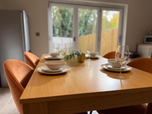 a wooden table with glasses and plates on it at Shenley House with Private Parking Central MK in Milton Keynes