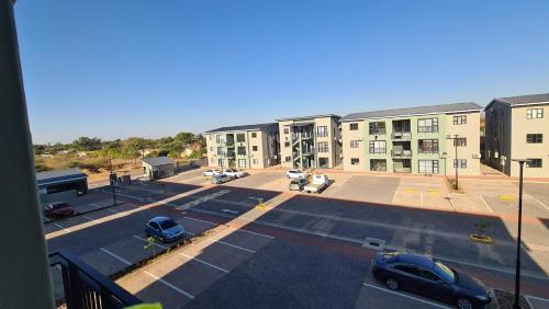 a view of a parking lot with a large building at Cozy 1-Bed Apartment in Gaborone in Gaborone