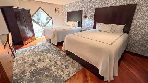 ein Hotelzimmer mit zwei Betten und einem Fenster in der Unterkunft Santa Rita Hotel del Arte in Zacatecas