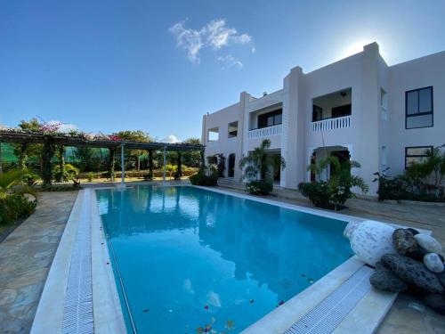a swimming pool in front of a white house at Vipingo Luxury Villa in Kilifi