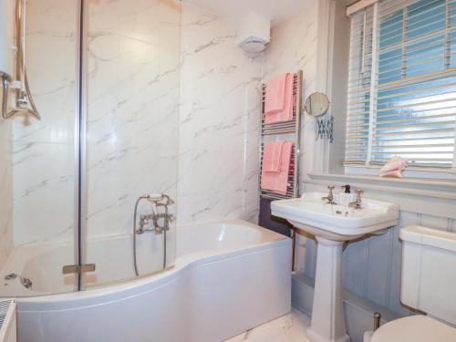 a white bathroom with a tub and a sink at Tradewinds in Newquay