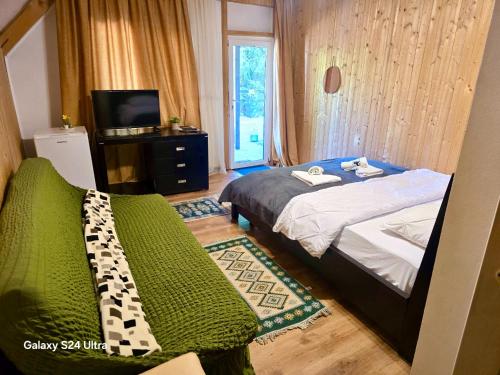 a bedroom with a bed and a tv and a bed sidx sidx sidx at Casa dintre Brazi Colibita in Colibiţa