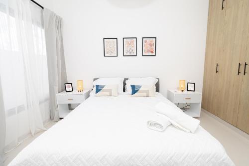 a white bedroom with a large white bed with two night stands at Cozy 1-BR Apartment in Bayahibe in San Rafael del Yuma