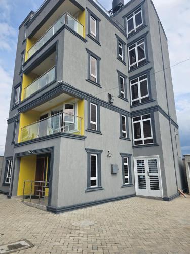un grand bâtiment gris aux finitions jaunes dans l'établissement Twin Paradise Homes, à Nairobi