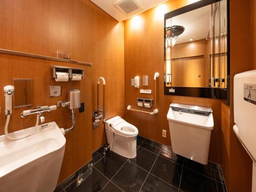 a bathroom with a toilet and a sink and a mirror at APA Hotel Nagoya Sakae Higashi in Nagoya