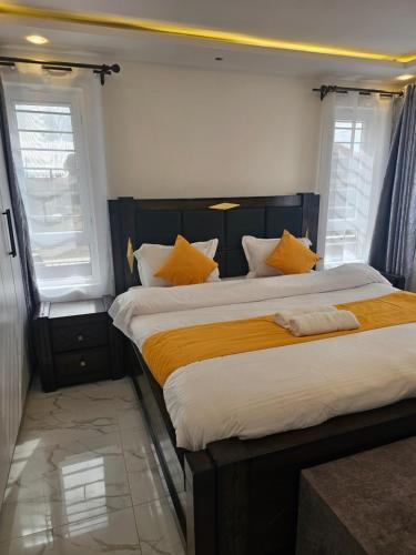 une chambre avec un grand lit avec des oreillers jaunes dans l'établissement Twin Paradise Homes, à Nairobi