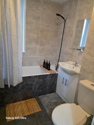 a bathroom with a tub and a toilet and a sink at Green & White Haven-Spacious 3BR in London