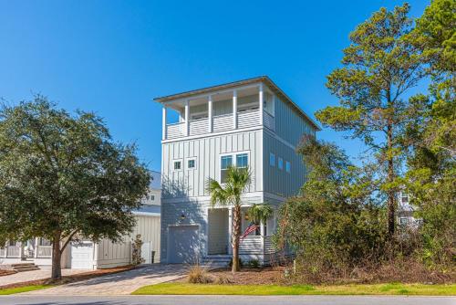 ein weiß-graues Haus mit einem Baum in der Unterkunft Vitamin Sea in Inlet Beach