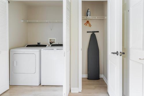 ein weißer Waschraum mit zwei Waschmaschinen und einem Bindeband in der Unterkunft Blueground Santa Clara pool nr Central Park SFO-2067 in Agnew