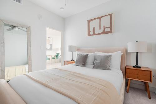 ein weißes Schlafzimmer mit einem Bett und einem Spiegel in der Unterkunft Blueground East Industrial pool nr Central Park SFO-2045 in Warm Springs District