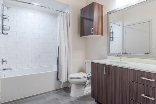 ein Badezimmer mit Toilette, Waschbecken und Spiegel in der Unterkunft Blueground East Industrial pool nr Central Park SFO-2045 in Warm Springs District