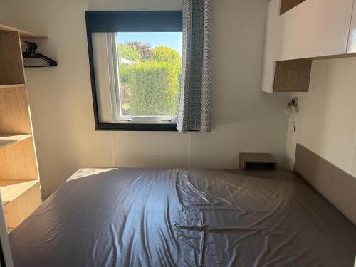a bedroom with a bed and a window at Mobil-home 33 st jean de monts camping 5 étoiles in Saint-Jean-de-Monts