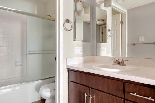 a bathroom with a sink and a toilet and a mirror at Blueground Campbell pool nr Campbell Park SFO-1998 in Campbell
