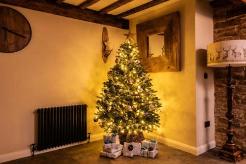 a christmas tree in the corner of a room at Homestead - Cosy Cotswolds Cottage with Hot Tub in South Cerney
