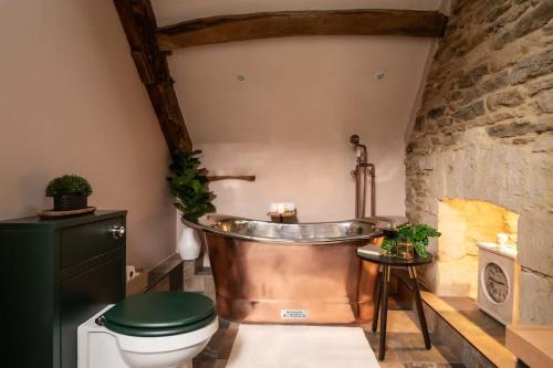 a bathroom with a copper tub and a toilet at Homestead - Cosy Cotswolds Cottage with Hot Tub in South Cerney