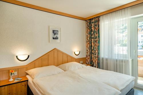 a bedroom with a white bed and a window at Studio Appartement Haus Voglreiter in Kaprun