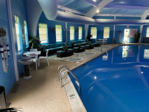 a large swimming pool in a building with blue walls at Stunning! Pocono Escape! HotTub Sauna Pool Ski Pet-Friendly Firepit Game Room Fireplace BBQ Lakes Tennis Fishing in Long Pond