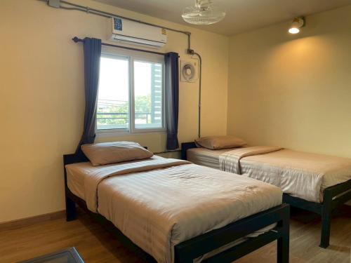 two beds in a room with a window at Banhor Residence in Chiang Mai