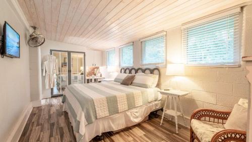 een slaapkamer met een bed, een stoel en ramen bij The Shipwright's Bungalow in Saint Simons Island
