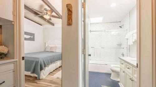 een slaapkamer met een bed en een badkamer met een wastafel bij The Shipwright's Bungalow in Saint Simons Island