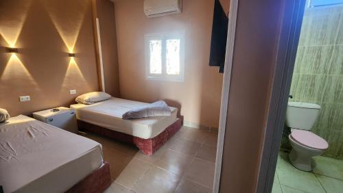 a small bedroom with two beds and a toilet at Shapon Hotel - Hurghada in Hurghada