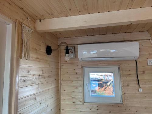 a room with a television and a window in a wooden wall at A Frame la Iaz in Mărăcineni