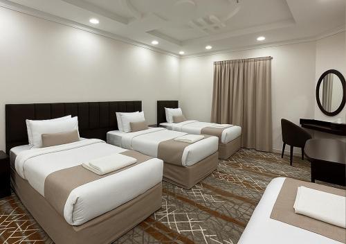 a hotel room with two beds and a desk at فندق التاج ثلاثة مكة in Mecca