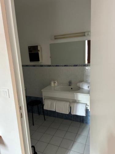 a bathroom with a tub and a sink and a mirror at Hotel Du Rocher in Le Caylar