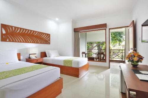 a hotel room with two beds and a desk with a desk at Dewi Sri Hotel in Legian