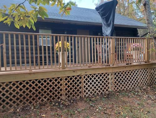 eine Holzterrasse mit einem Zaun vor einem Haus in der Unterkunft Cozy Cabin for Two by the Lake for a Peaceful Escape in Opelika, Alabama in Opelika