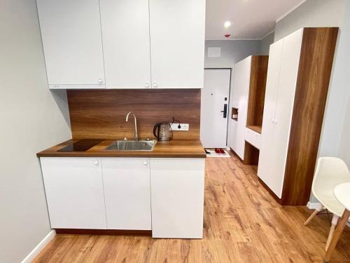 a kitchen with white cabinets and a wooden floor at La Vita Batumi in Batumi