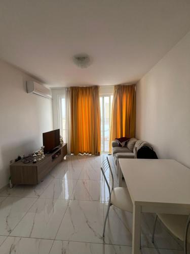 a living room with a couch and a tv at Jasmine court penthouse in Tal-Ħriereb
