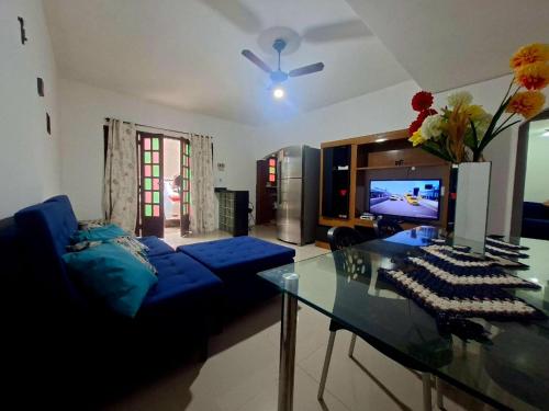 a living room with a blue couch and a glass table at Temporada na Praia do Trevo - Rio das Ostras, RJ in Rio das Ostras