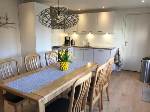 Una cocina con una mesa de madera con sillas y un comedor. en Pinkeltje, en Aagtekerke