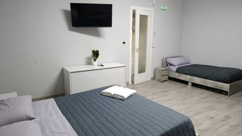 a bedroom with two beds and a tv on the wall at Suites GREY in centro Randazzo in Randazzo