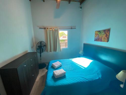 a blue bedroom with a bed with two towels on it at Cabañas Cruz del Sur in Miramar