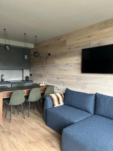a living room with a blue couch and a tv at Casa d'Alpe -Boutique apartment Chaberton view in San Sicario
