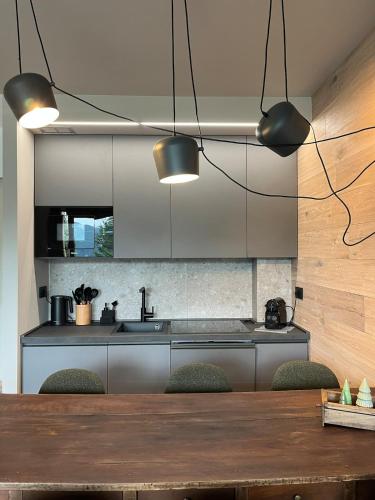 a kitchen with a table with chairs and two lights at Casa d'Alpe -Boutique apartment Chaberton view in San Sicario