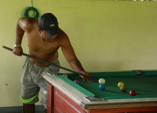 Un hombre jugando al billar con un taco en una mesa de billar en Ecopousada Bacabas - Hotel, Camping e Balneário, en Santa Isabel do Pará
