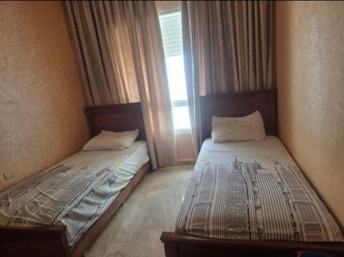 two twin beds in a room with a window at Residence kettani in Bouznika