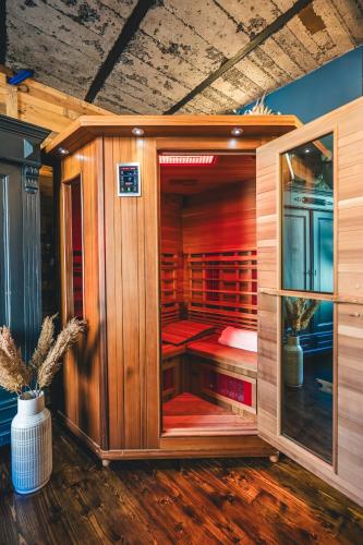 a wooden sauna with a glass door in a room at L'Atelier - Gîte chaleureux et relaxant in Saint-Hubert