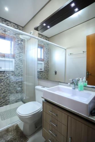 a bathroom with a sink and a toilet and a mirror at Casa Petri Gramado casa inteira para 7 pessoas ideal para famílias in Gramado